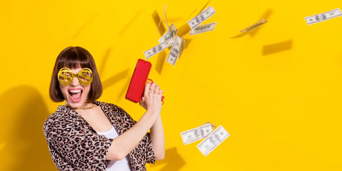 Excited woman celebrating Lotto MAX jackpot win with money flying around against a vibrant yellow background.